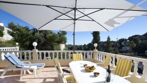 An outdoor patio with a white table, striped chairs, and a large umbrella. - Vacation home Alexia by Interhome (Benissa)
