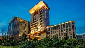 A modern hotel with a prominent tower, multiple floors, and a well-lit entrance. - Yungang Jianguo Hotel (Datong)