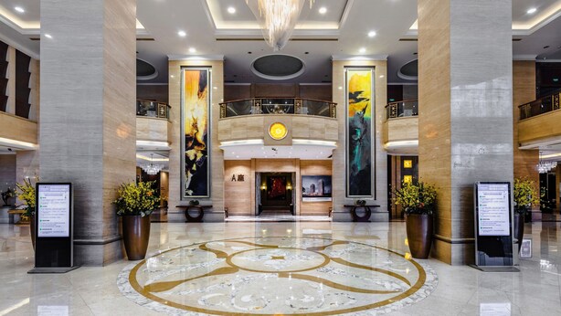 A spacious lobby with a central chandelier, marble flooring, and large vertical artworks. - Yungang Jianguo Hotel (Datong)