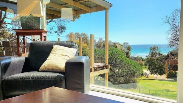 A modern living room with a large window overlooking a coastal landscape. - Settlers Cottage - Snellings Beach - Kangaroo Island (Middle River)