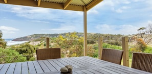 A wooden table with two chairs and a view of the coastline. - Settlers Cottage - Snellings Beach - Kangaroo Island (Middle River)