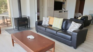 A living room with a sofa, coffee table, and a fireplace. - Settlers Cottage - Snellings Beach - Kangaroo Island (Middle River)