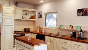 A kitchen with white cabinetry, a wooden countertop, a built-in oven, and a window. - Settlers Cottage - Snellings Beach - Kangaroo Island (Middle River)