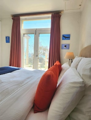 A hotel room with a bed, a window with curtains, a lamp, and wall art of birds. - Settlers Cottage - Snellings Beach - Kangaroo Island (Middle River)
