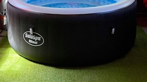 A round hot tub with a blue interior, labeled "Saluspa Miami," placed on a green carpet. -  hot tub, grill, fireplace, Hocking Hills, Buckeye Lake, Legend Valley (Somerset)