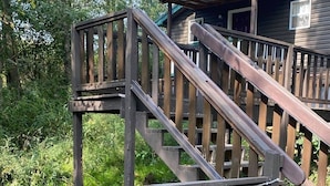 A wooden staircase leading to a cabin with a green roof, surrounded by greenery. -  hot tub, grill, fireplace, Hocking Hills, Buckeye Lake, Legend Valley (Somerset)