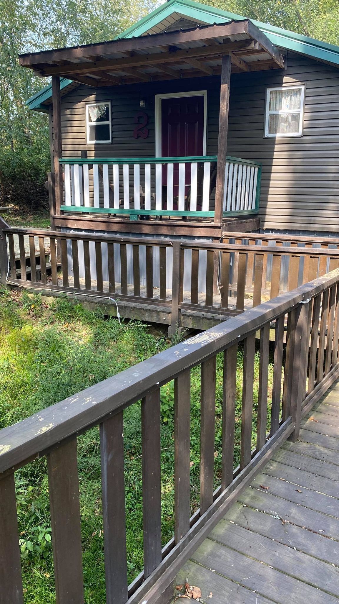 A wooden cabin with a porch, a small window, and a door.