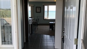 Corredor que dá para um quarto com vista para o mar, área de refeições e cozinha.