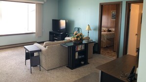 Uma sala de estar com sofá, televisão, abajur e estante de livros.