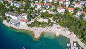 An aerial view of a coastal town with a beach, residential buildings, and a marina. - Villa Estrella (Dramalj)