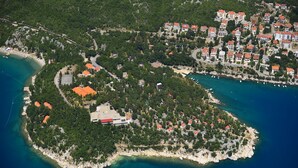 An aerial view of a coastal town with dense greenery, a central open area, and buildings with red roofs. - Villa Estrella (Dramalj)