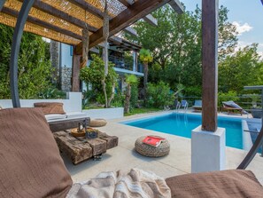 Un espace aménagé au bord de la piscine, avec une terrasse en bois, des chaises longues et une piscine.