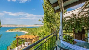 A balcony with a view of a beach and sea, a pool, and outdoor seating. - Villa Fun Haus 2 (Jadranovo)