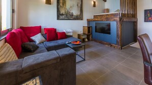 A living room with a grey sofa, red cushions, a wooden entertainment unit, a fireplace, and a large painting on the wall. - Villa Fun Haus 2 (Jadranovo)