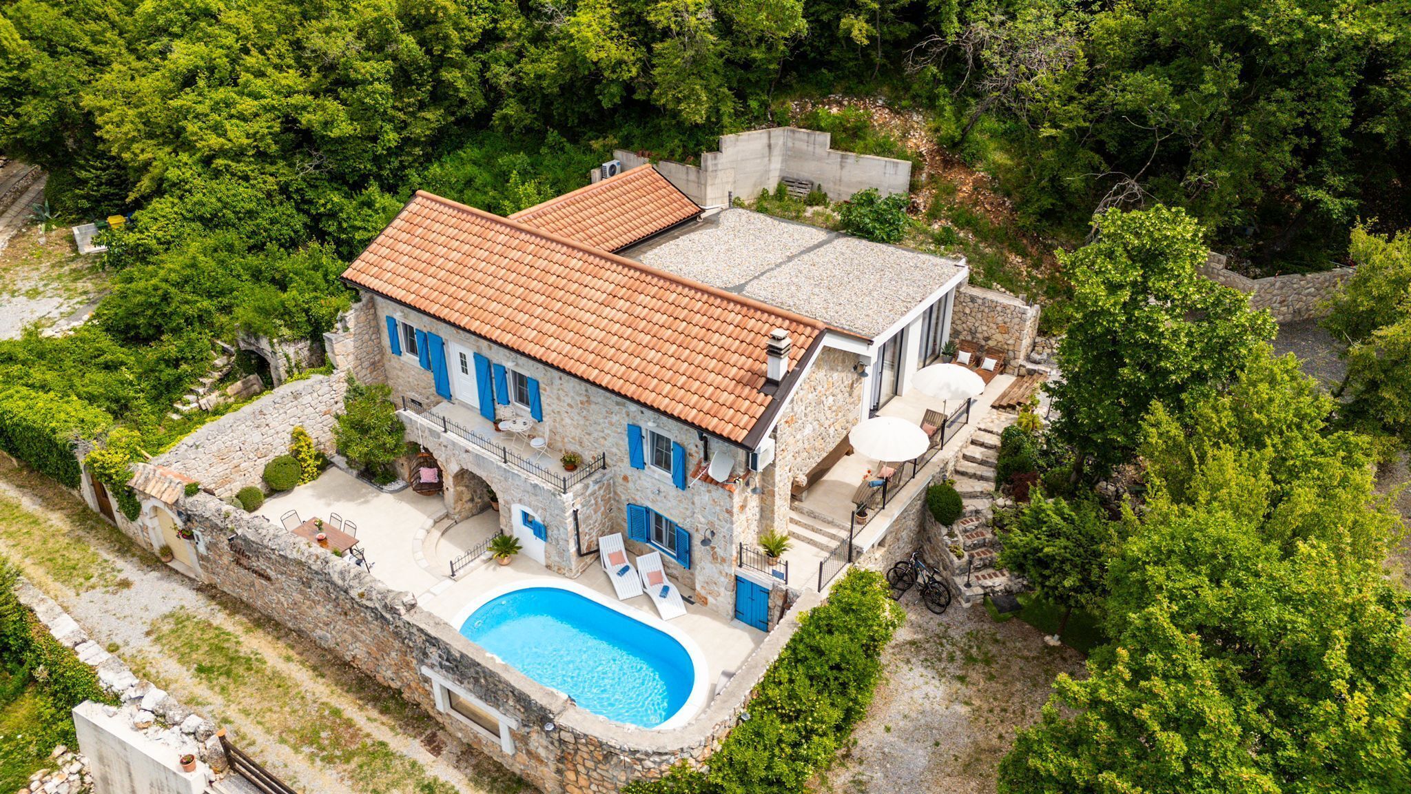 A stone house with a swimming pool, a terrace, and a garden.