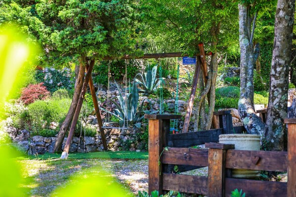 A wooden fence with a rustic garden setting, including various plants and a stone wall in the background. - Villa Siesta (Grizane)
