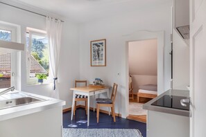 A compact room with a kitchenette, a dining area, and a bed.