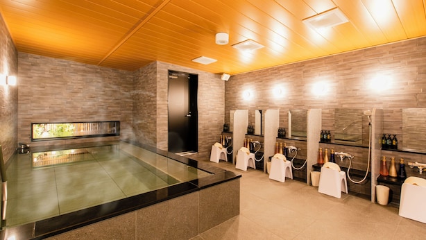 Moderni spa-alue, jossa on lasiseinillä varustettu poreallas, useita pesualtaita ja puinen katto.