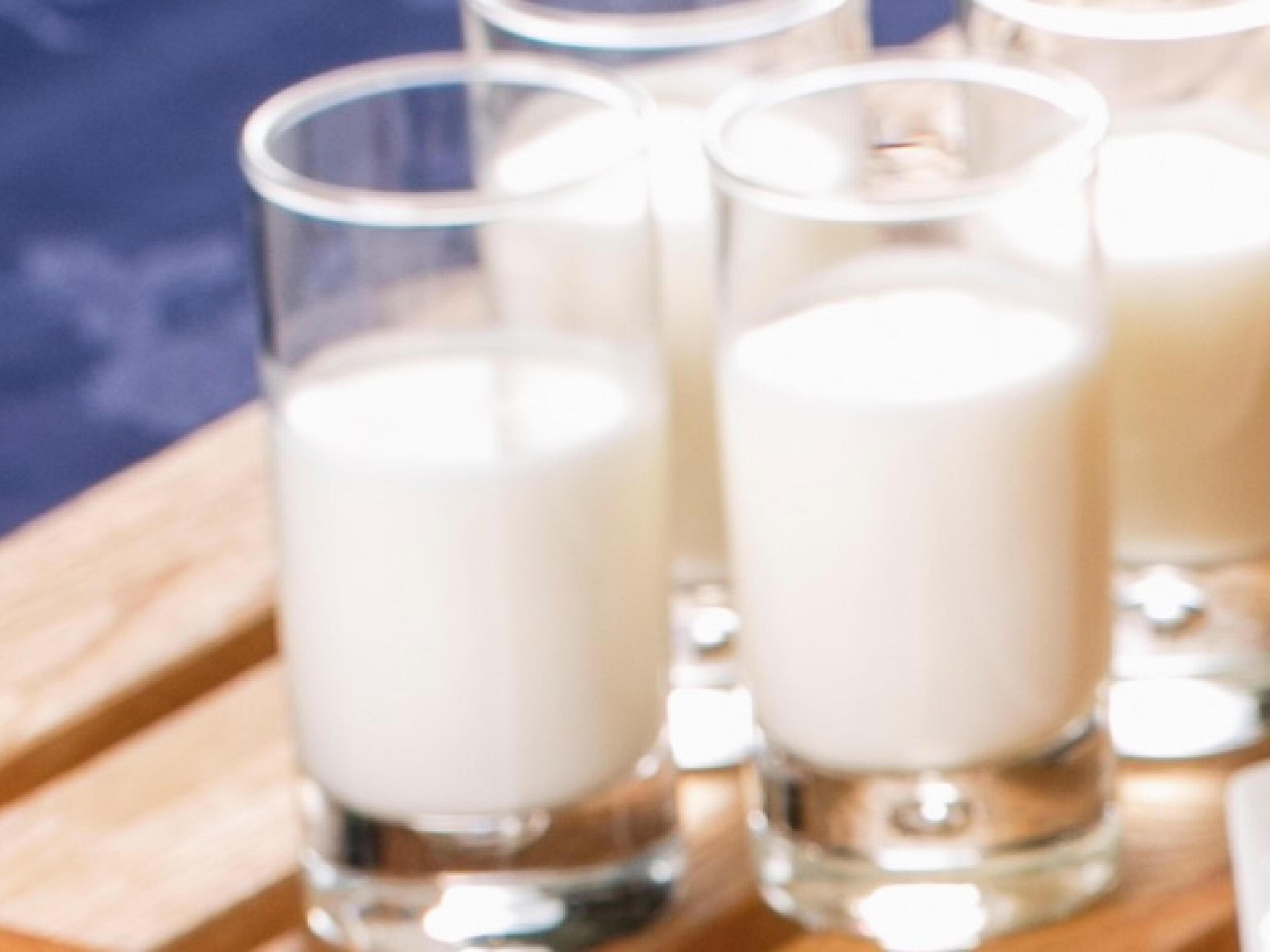 A wooden tray with several clear glasses filled with a white liquid, likely milk or a similar beverage.