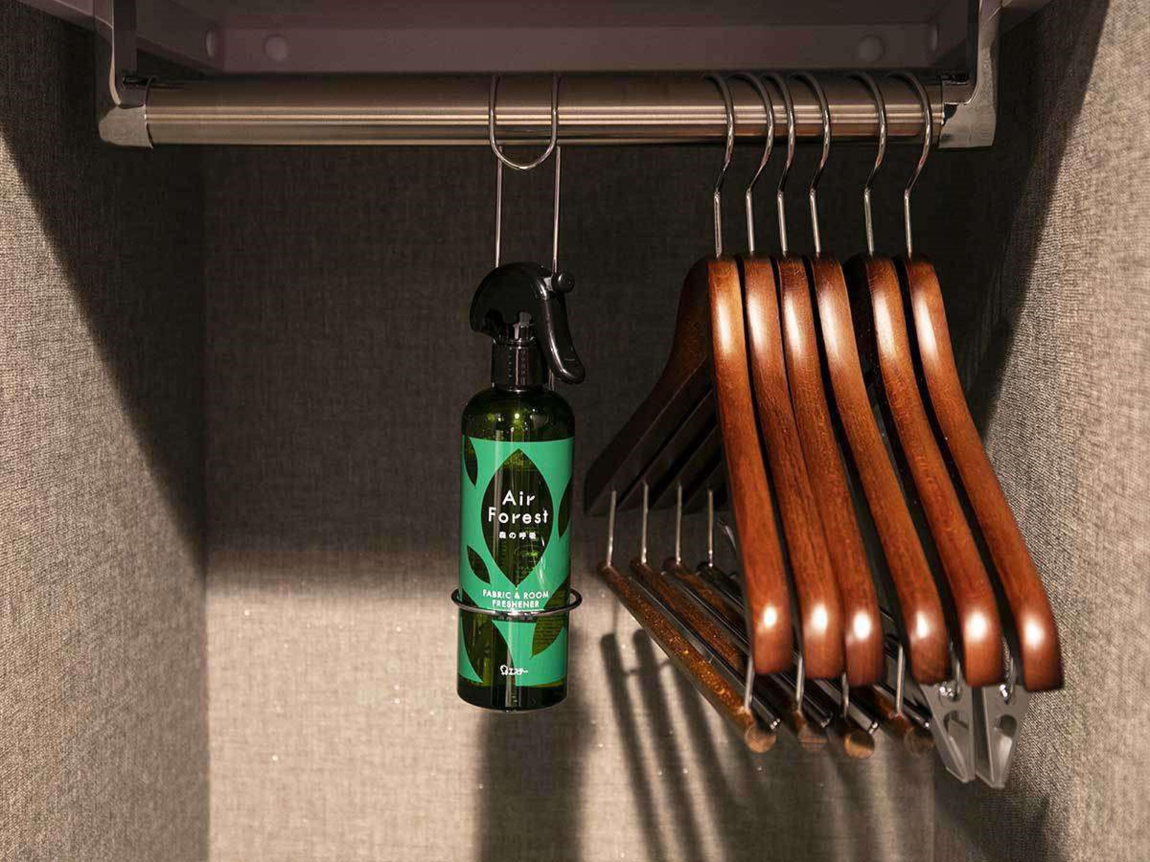 A bottle of Air Forest fabric and room freshener hanging on a metal rod.