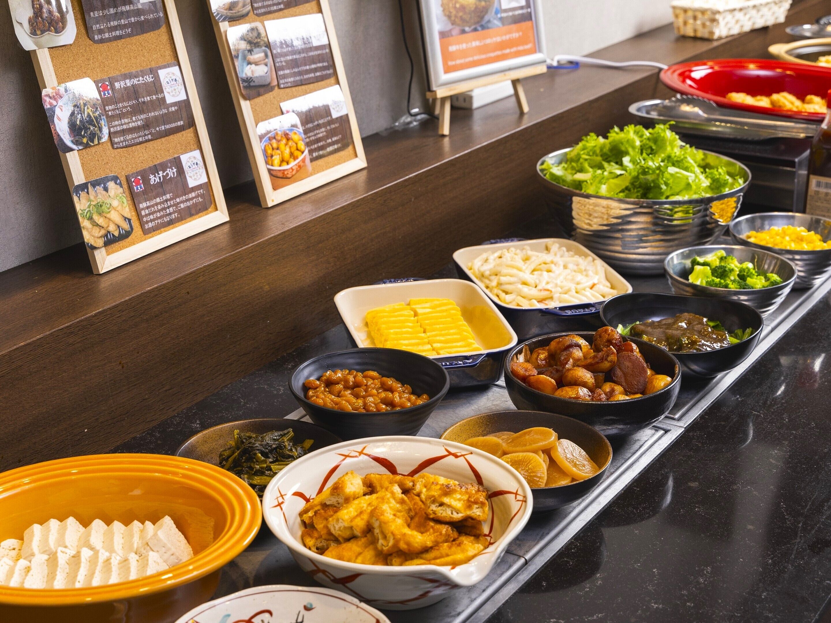 Un buffet proposant une variété de plats, notamment des salades, des viandes et des légumes.
