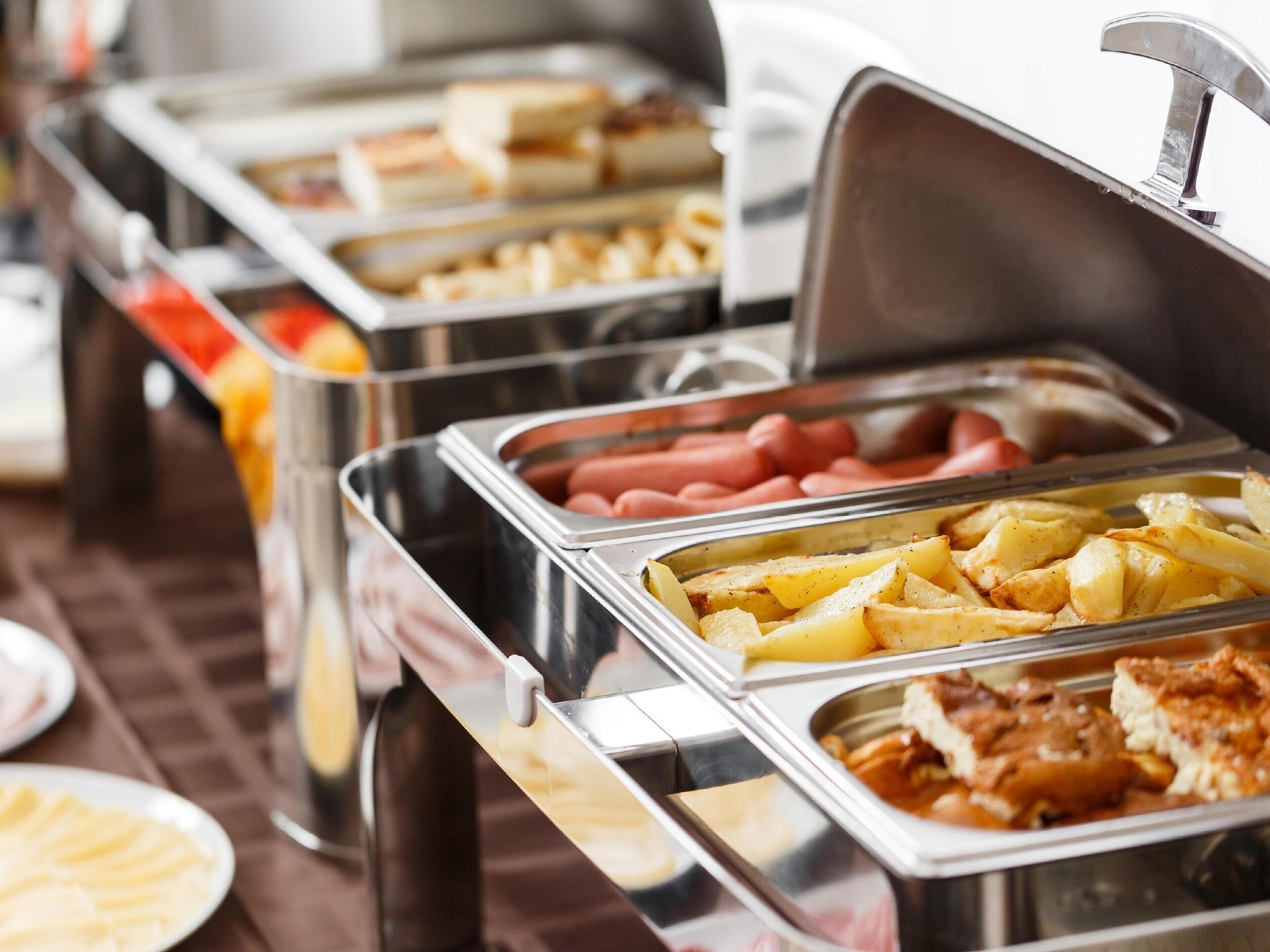 A buffet with various food items including hot dogs, potatoes, and other dishes.