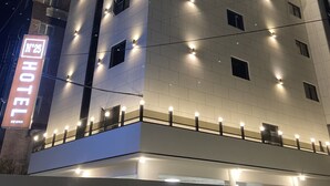 A multi-story hotel with illuminated signage, a flat facade, and evenly spaced windows. - Gijang No.25 Hotel (Busan)