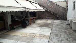 Un patio con suelo de baldosas, una mesa de madera, una hamaca y una escalera.