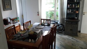 Un coin repas avec une table en verre, des chaises en bois et un vélo en arrière-plan.