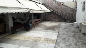 A courtyard with a tiled floor, a wooden table, a hammock, and a staircase.