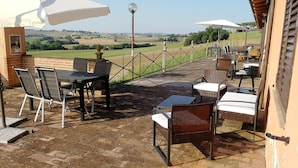 Eine Außenpatio mit Tisch und Stühlen, Blick ins Grüne und einer Umzäunung.