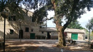 A courtyard with stone paving, a tree, and a building with a tiled roof. - Double Twin Room Private Bathroom for Swimming Pool use (Treia)