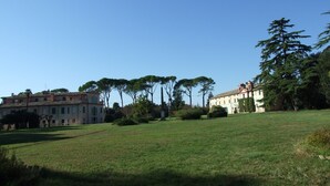 A grassy field with a building and trees in the background. - Double Twin Room Private Bathroom for Swimming Pool use (Treia)