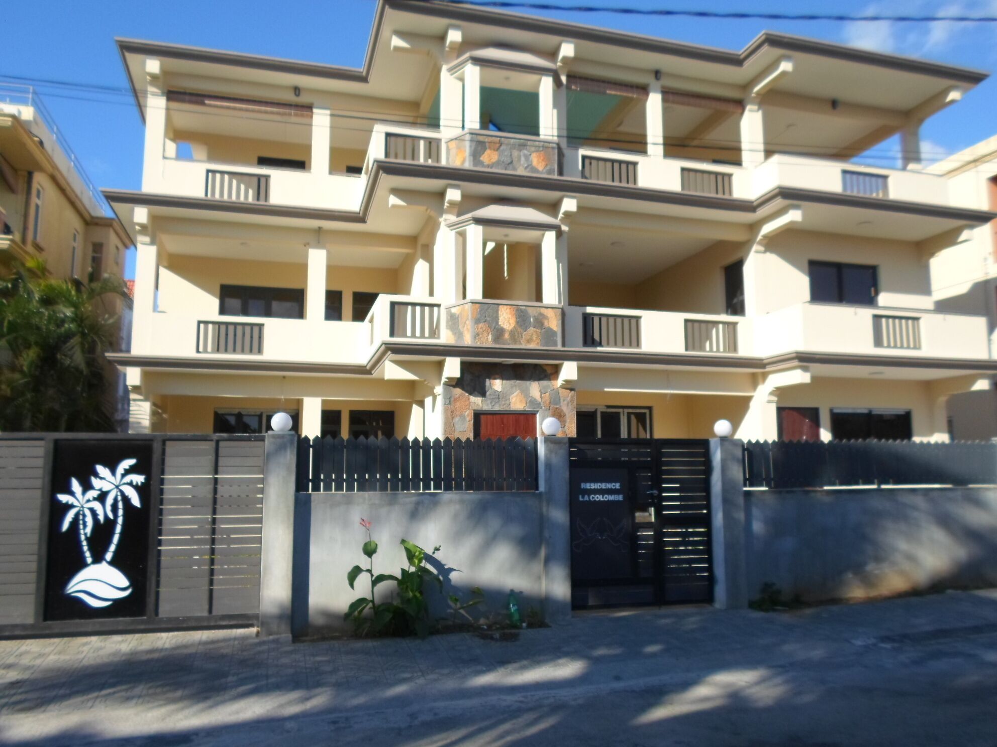A multi-story residential building with balconies, a gated entrance, and a sign indicating 'RESIDENCE LA COLOMBE'.