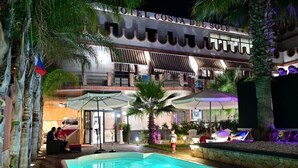 A hotel with a pool area, outdoor seating, and a well-lit entrance. - Costa del Sole Apartment 50 Meters From the Beach of the Catania Coast (Catania)