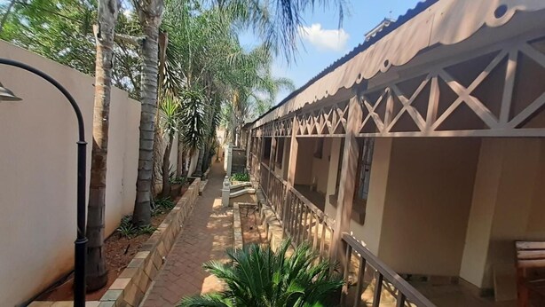 A narrow pathway flanked by buildings with traditional architecture, including a covered walkway and a building with a patterned facade. - Karl Heyne Guesthouse Double Room (Rustenburg)