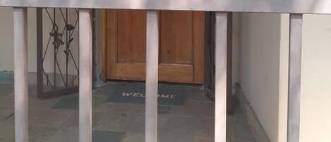 Una puerta de madera con un panel de vidrio, un portón de metal y un suelo de baldosas.