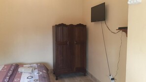 A bedroom with a bed, a wardrobe, a TV mounted on the wall, and a power outlet. - Karl Heyne Guesthouse Double Room (Rustenburg)