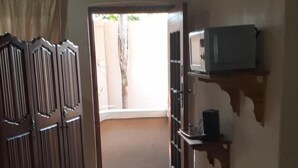 A hallway with a wooden floor, a wardrobe, a microwave on a shelf, and a door leading to an outdoor area. - Spacious Double Room in Lovely Guesthouse (Rustenburg)