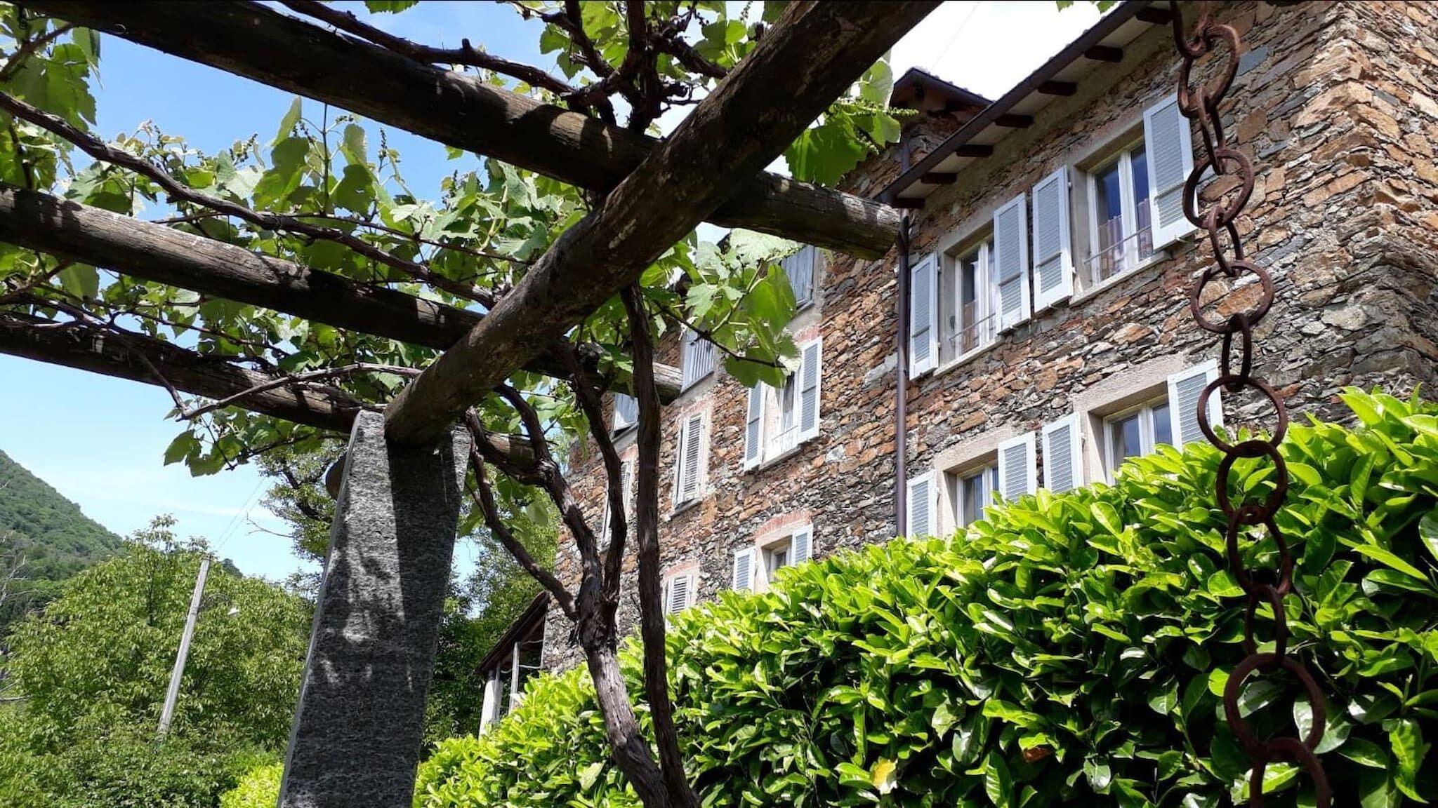 Un edificio de piedra con múltiples ventanas y una pérgola de madera.