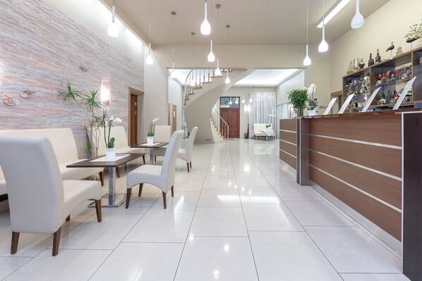 Un vestíbulo de hotel moderno con mostrador de recepción, zona de estar y escalera.