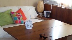 A wooden table with a white candle holder and sunglasses on it, a colorful cushion, and a basket on a wooden bench. - Akhir Cruise Charter (Salerno)