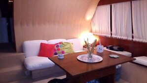 A modern living room with a white sofa, a wooden coffee table, and a lamp. - Akhir Cruise Charter (Salerno)