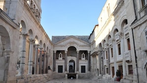 A courtyard with classical architecture, featuring columns and arches, and a central building with a pediment. - Kind Room -hotel Rose Split (Split)