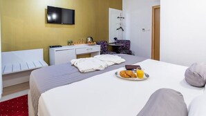 A hotel room with a bed, a TV mounted on the wall, a small desk with a chair, and a breakfast tray on the bed. - Kind Room -hotel Rose Split (Split)