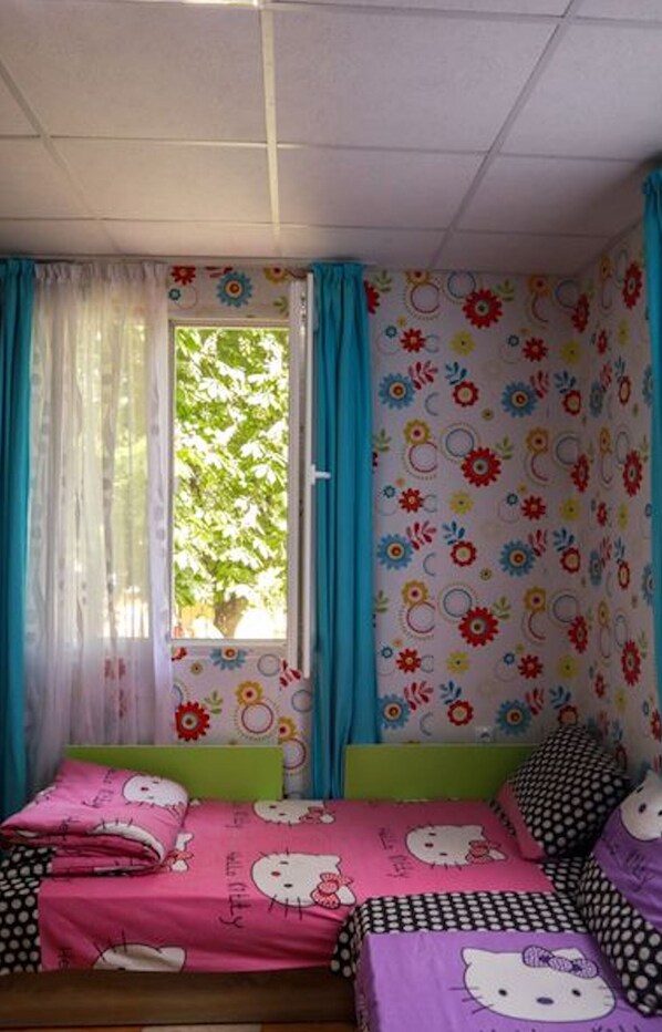 Um quarto com cama, cortinas e janela com vista para árvores.