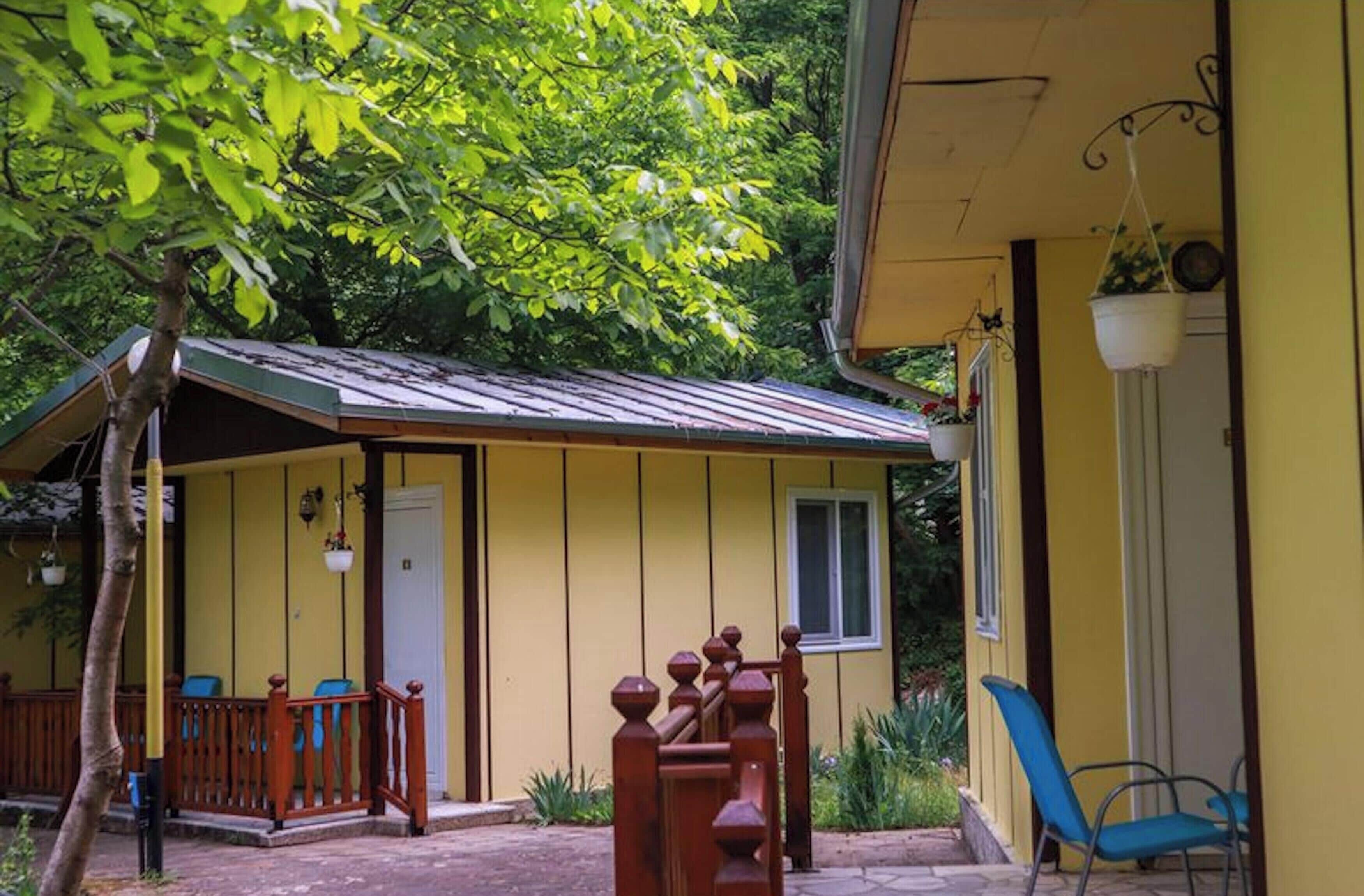 Un bâtiment jaune avec un porche, une petite fenêtre et une porte.