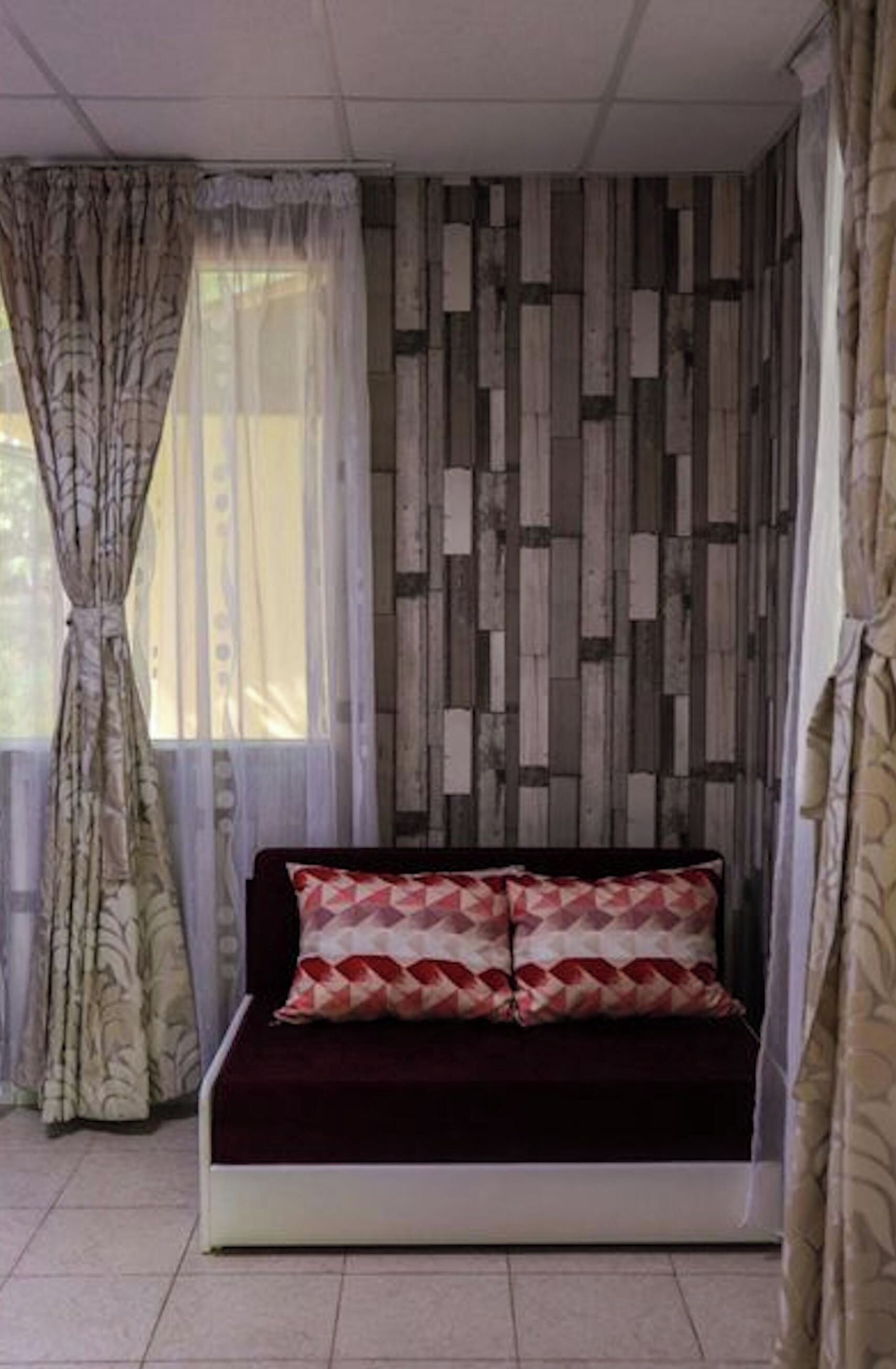 A room with a sofa, curtains, and a patterned wall.