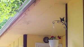 A room with a wooden railing, a white door with the number 28, and a hanging plant. - Bungalow in a Lovely Village Kamena (Petrich)