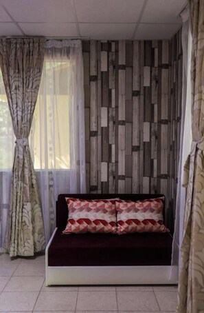 A room with a sofa, curtains, and a patterned wall. - Cosy Bungalow for 2 or 3 Persons (Petrich)
